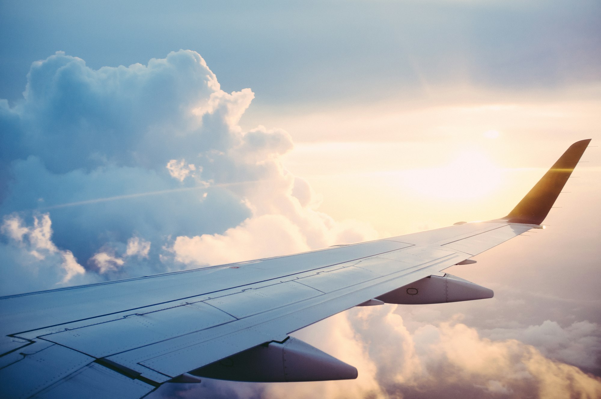 An airplane wing above a golden sea of clouds at sunset